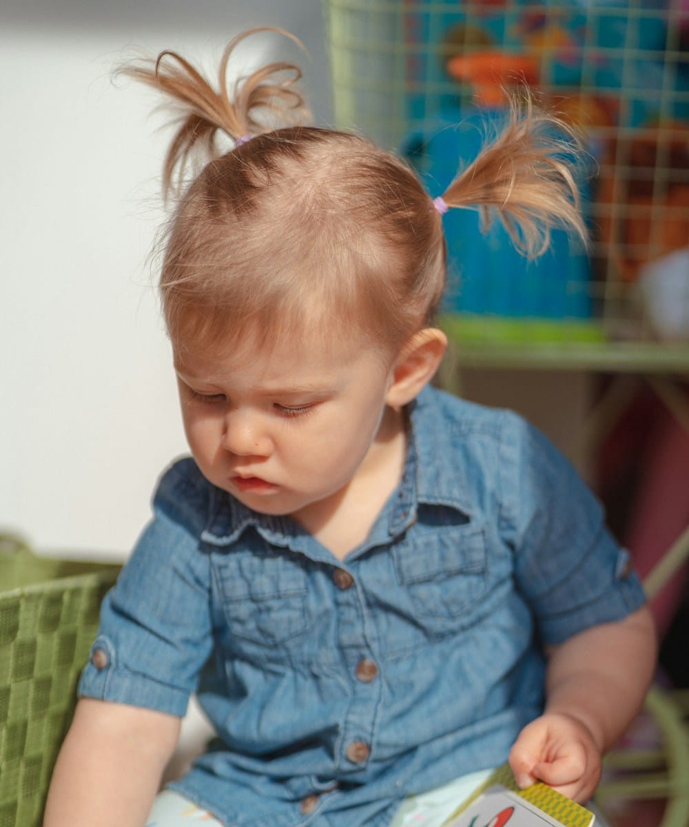 A young child sitting on the floor looking through a picture book